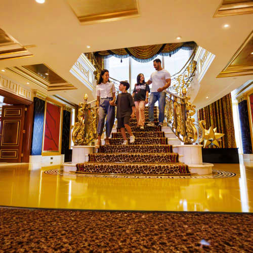 Guided Inside Burj Al Arab Tour Family walking down grand staircase with gold railings and skylights in luxury hotel interior lobby