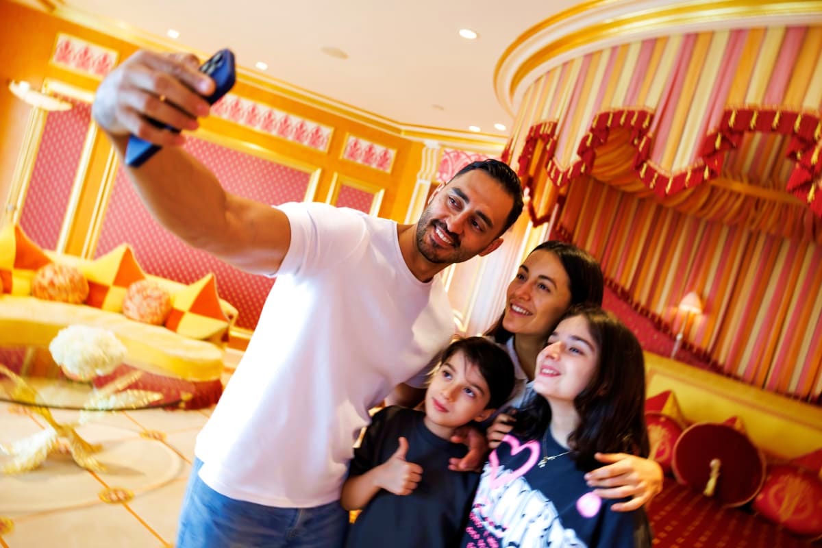 Family taking selfie inside Burj Al Arab luxury hotel with gold and red ornate interior decor