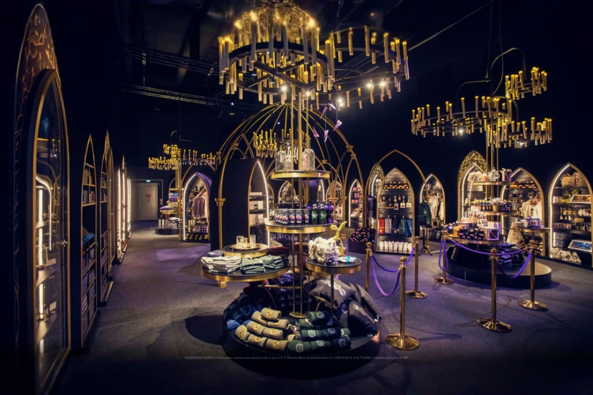 Harry Potter Visions of Magic Luxurious retail interior with Gothic-inspired architecture, gold pendant chandeliers, arched display cases, and purple velve
