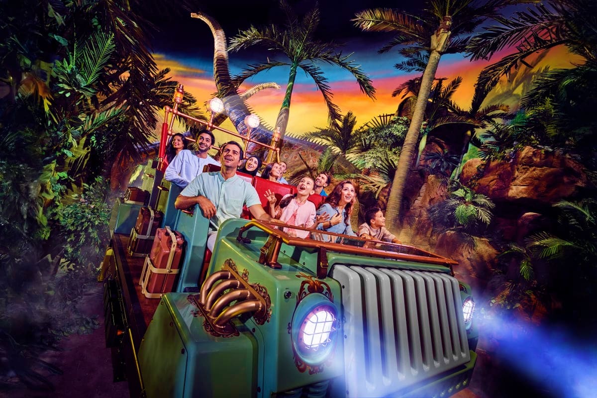 IMG Worlds of Adventure Family enjoying Jeep Ride dinosaur theme park attraction with animatronic dinosaur and tropical scenery at IMG Worlds of Adve