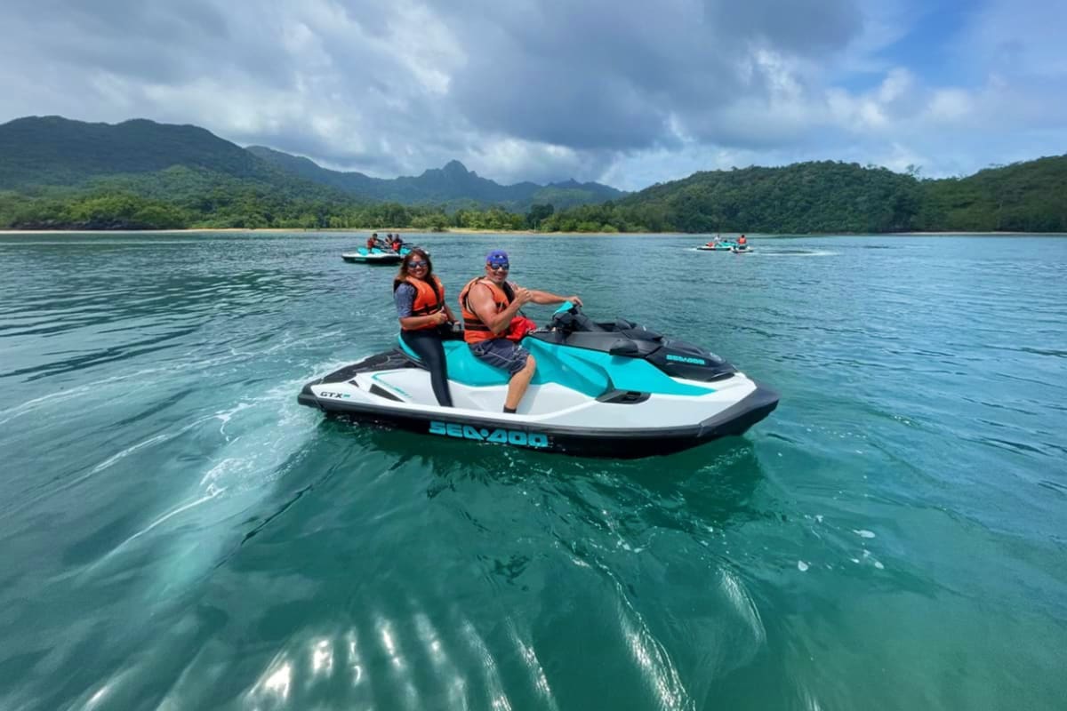 Jet ski at Cenang Beach Two people on a turquoise and white jet ski in clear tropical waters with lush green mountains in the background at Cenang Be