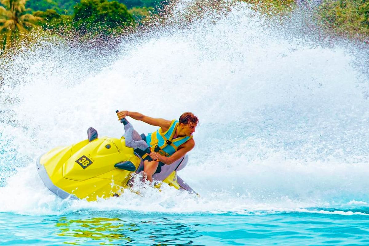 Jet ski at Cenang Beach Man riding yellow jet ski in turquoise waters at Cenang Beach with tropical vegetation visible on shore