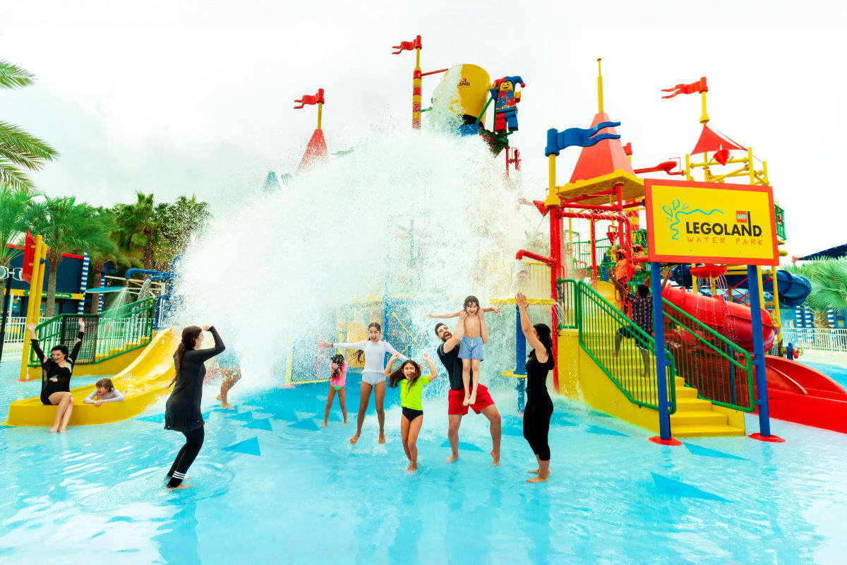 Families enjoying water attractions at LEGOLAND Water Park with colorful slides, splash features, and LEGO-themed structures