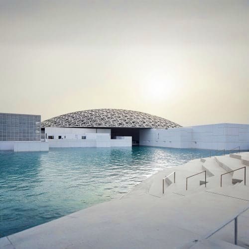 Louvre Abu Dhabi Louvre Abu Dhabi museum with distinctive dome reflected in waterfront lagoon at sunset