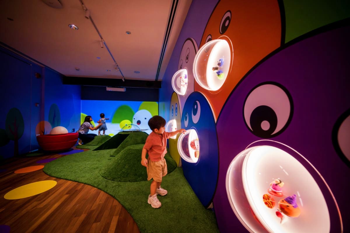 Child playing in interactive art installation with illuminated circular displays and colorful wall panels at National Gallery