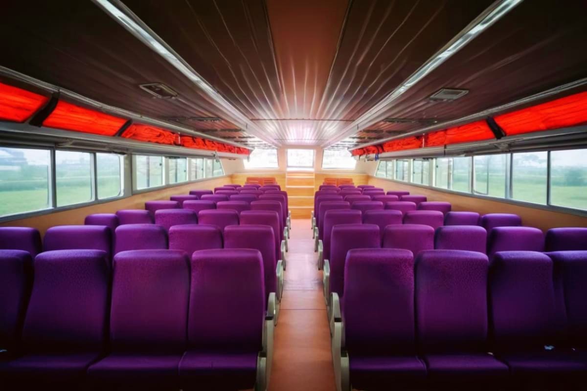 Nusa Penida Fast Boat Empty tour bus interior with purple seats, red overhead panels, and panoramic windows showing rural landscape view