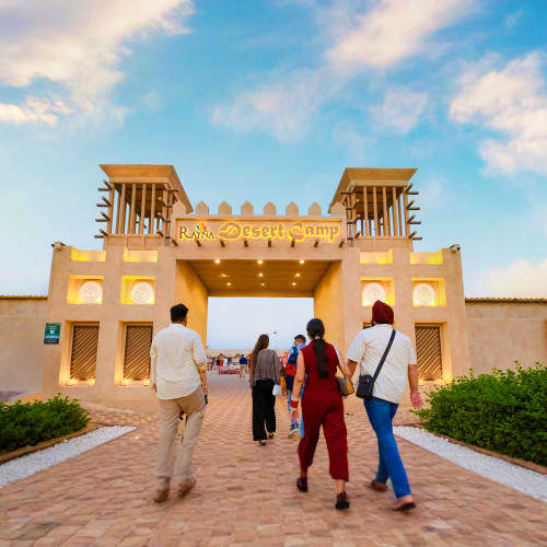 Private Desert Safari Dubai Visitors approaching the entrance gate of Ras Al Dhayah, a traditional Arabian fort-style structure in the Dubai desert with