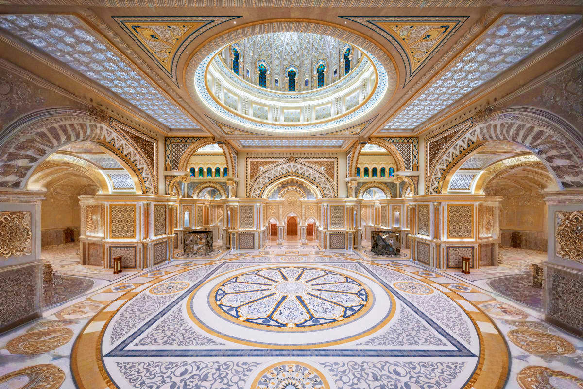 Ornate interior of Qasr Al Watan palace in Abu Dhabi featuring marble floors, decorated arches, and illuminated domed ceiling