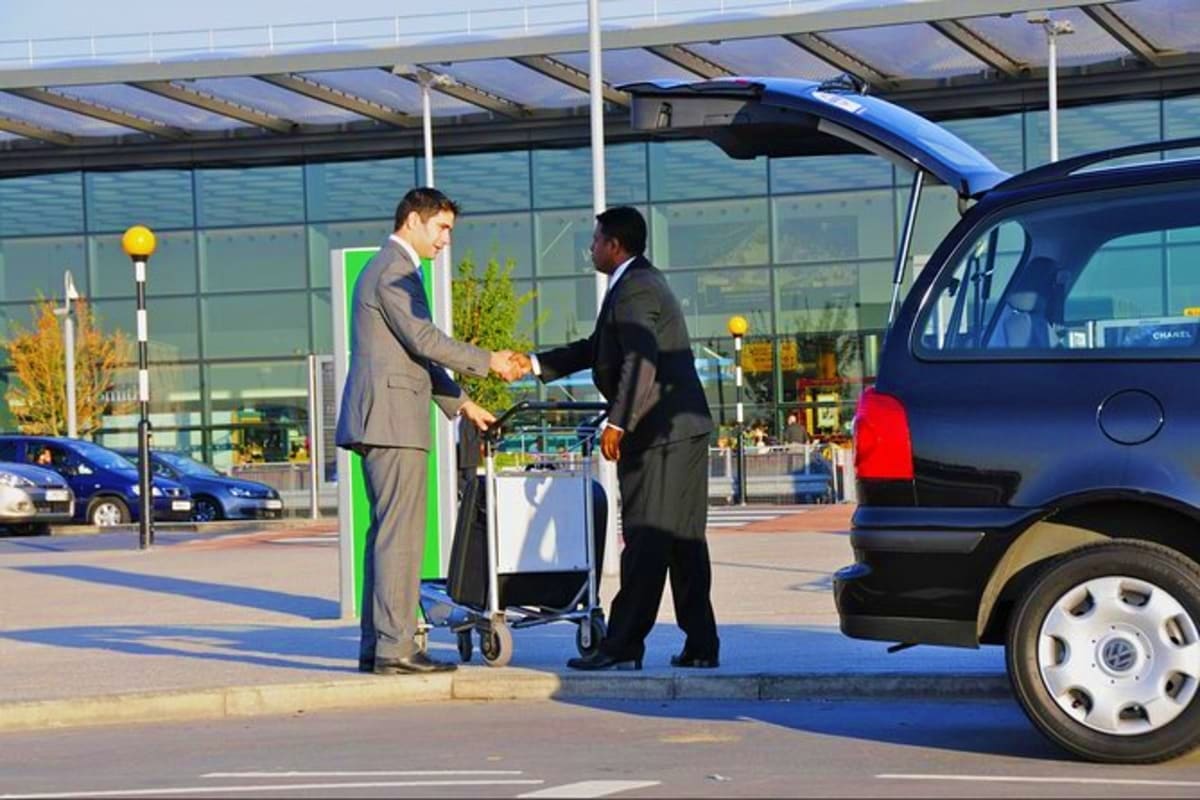 Singapore Cruise Pick up Two businessmen shaking hands at car rental facility with open trunk and luggage cart during Singapore cruise pickup service