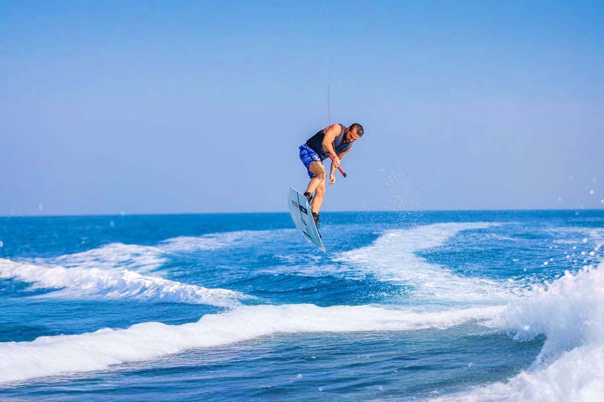 Man wakeboarding on blue ocean waves with clear sky in Dubai