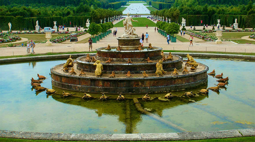Paris Arc de Triomphe Skip the Line Rooftop Tickets Ornate golden fountain with sculptures in formal garden pool at Palace of Versailles, with manicured grounds and visitors in