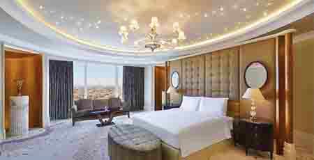 Riyadh Airport Pick up Luxury hotel bedroom with city view from floor-to-ceiling windows, king bed, and elegant furnishings