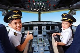 Two child pilots in uniform sitting in an aircraft cockpit at KidZania Singapore interactive experience