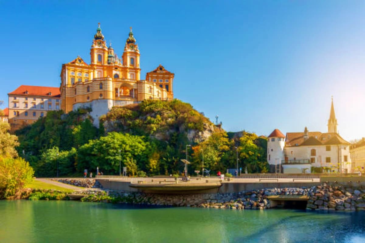 Melk Abbey monastery with yellow baroque church towers on hilltop overlooking Danube River in Austria
