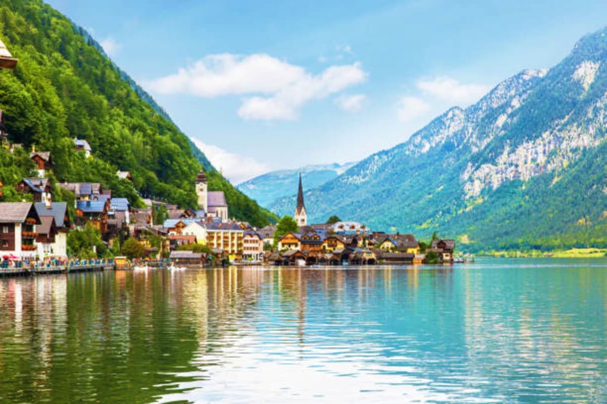 Hallstatt village reflected in alpine lake with forested mountains, Austria