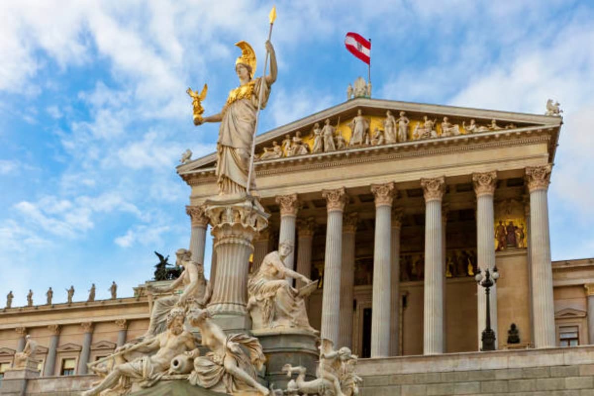 Austrian Parliament building in Vienna with Pallas Athena statue and red-white-red flag against blue sky