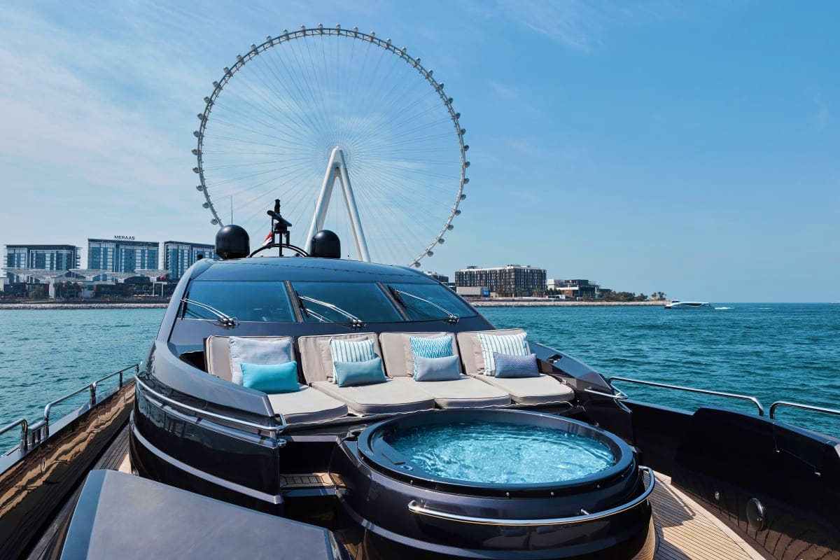 Luxury yacht deck with hot tub and seating area, London Eye Ferris wheel visible in background on Thames River