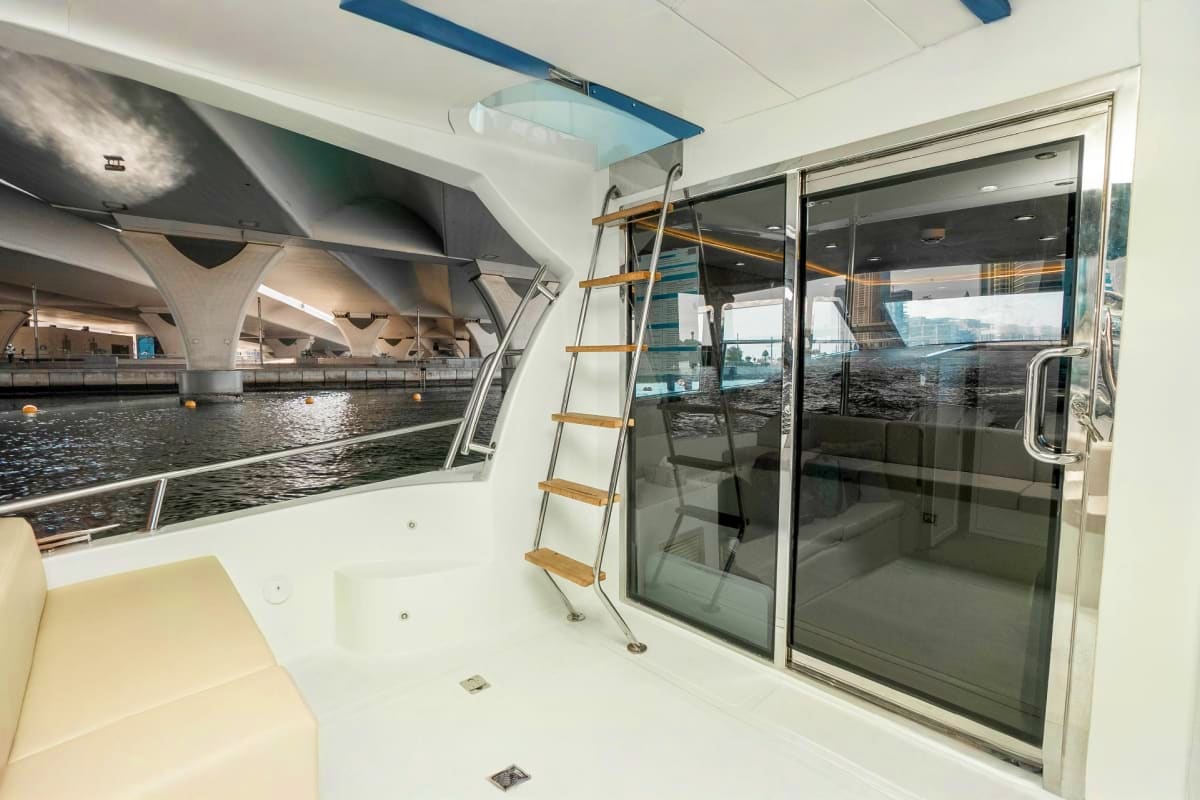 Modern yacht cabin interior with sliding glass doors, wooden ladder, and panoramic windows overlooking urban waterfront