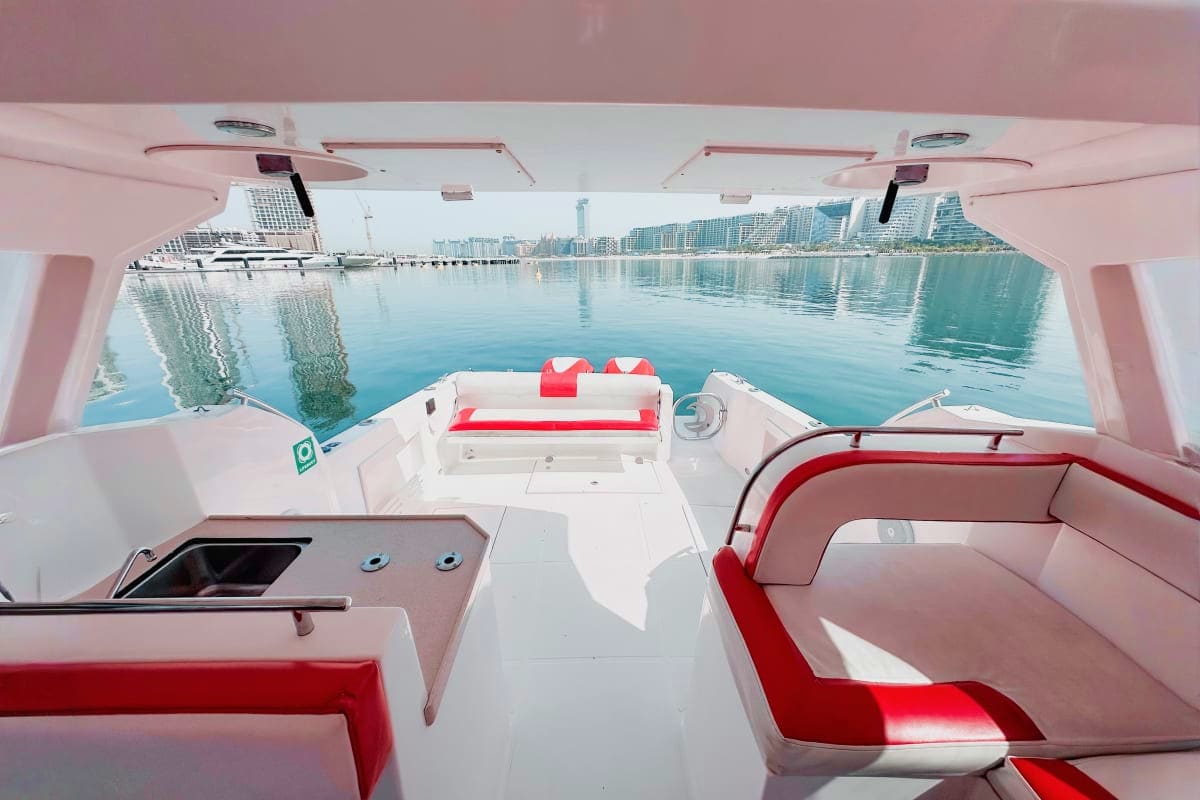 Silver Craft X13 Interior view of Silver Craft X13 yacht cabin with red and white seating, looking out toward marina and city skyline across c