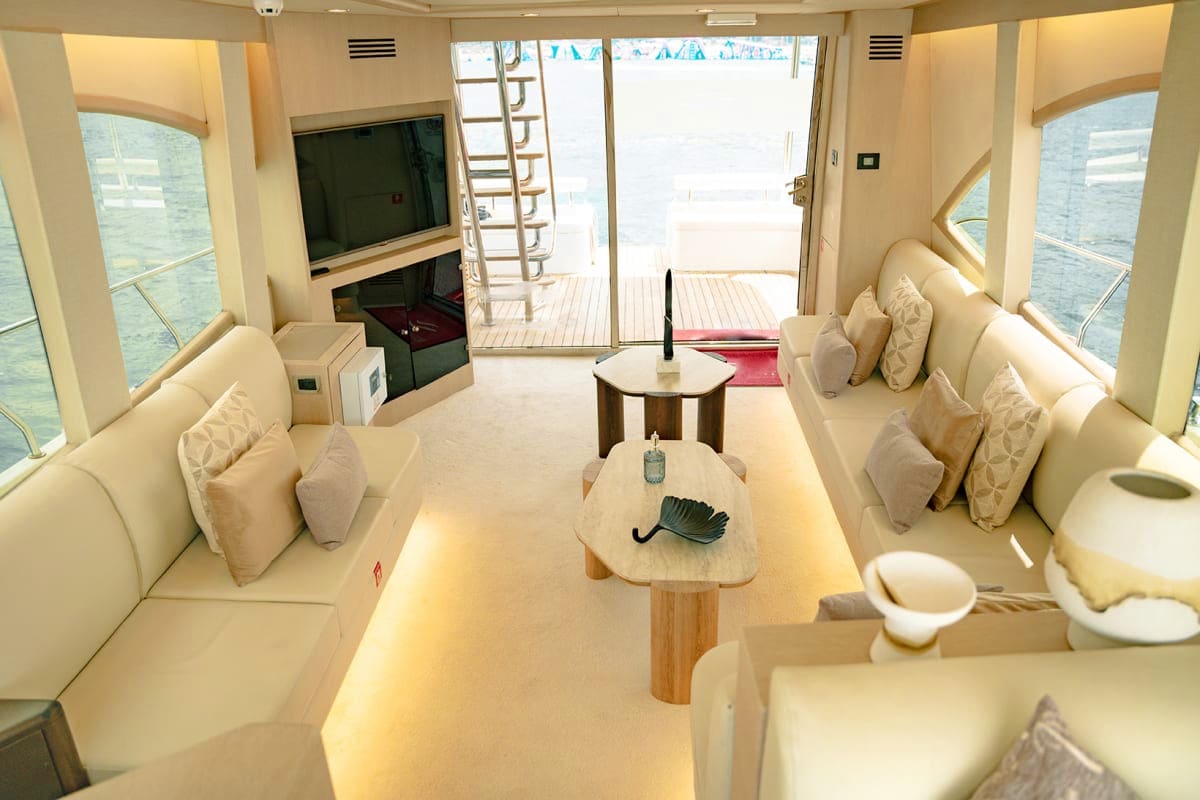 Duretti X1 Duretti X1 yacht interior living space with cream-colored seating, wooden tables, flat-screen TV, and open deck access with w