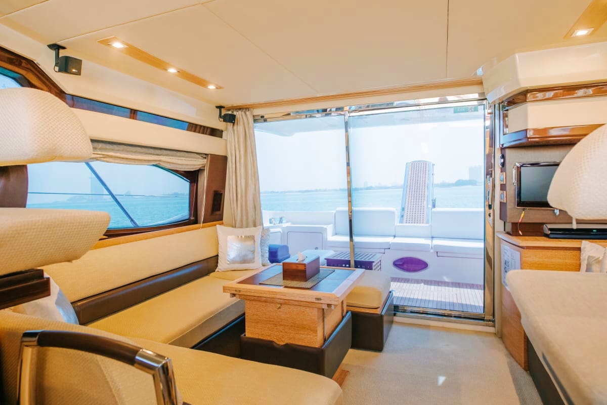 48 Ft Ocean Beat Yacht Luxury yacht interior cabin with cream and wood furnishings, ocean view through large windows, seating area and entertainment