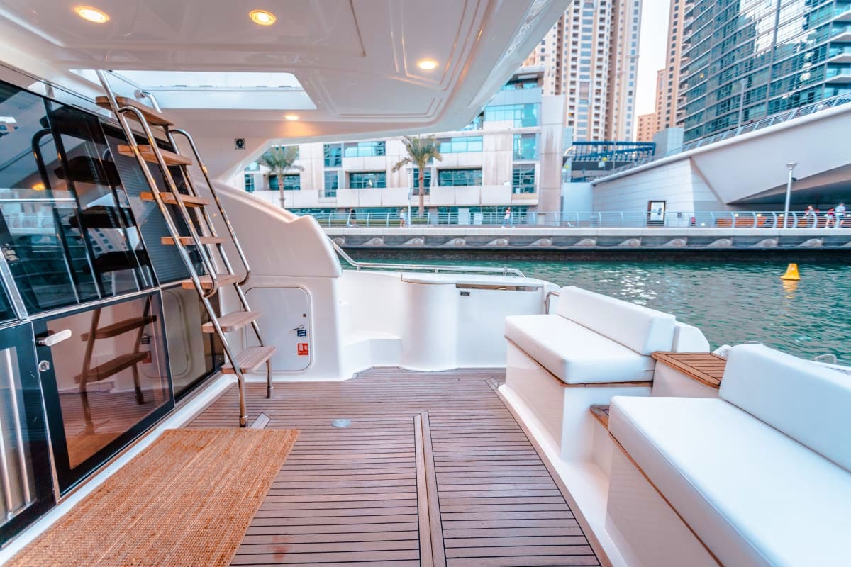 Luxury yacht 50 Ft Aliona deck with white seating, wooden flooring, and urban waterfront cityscape with high-rise buildings v