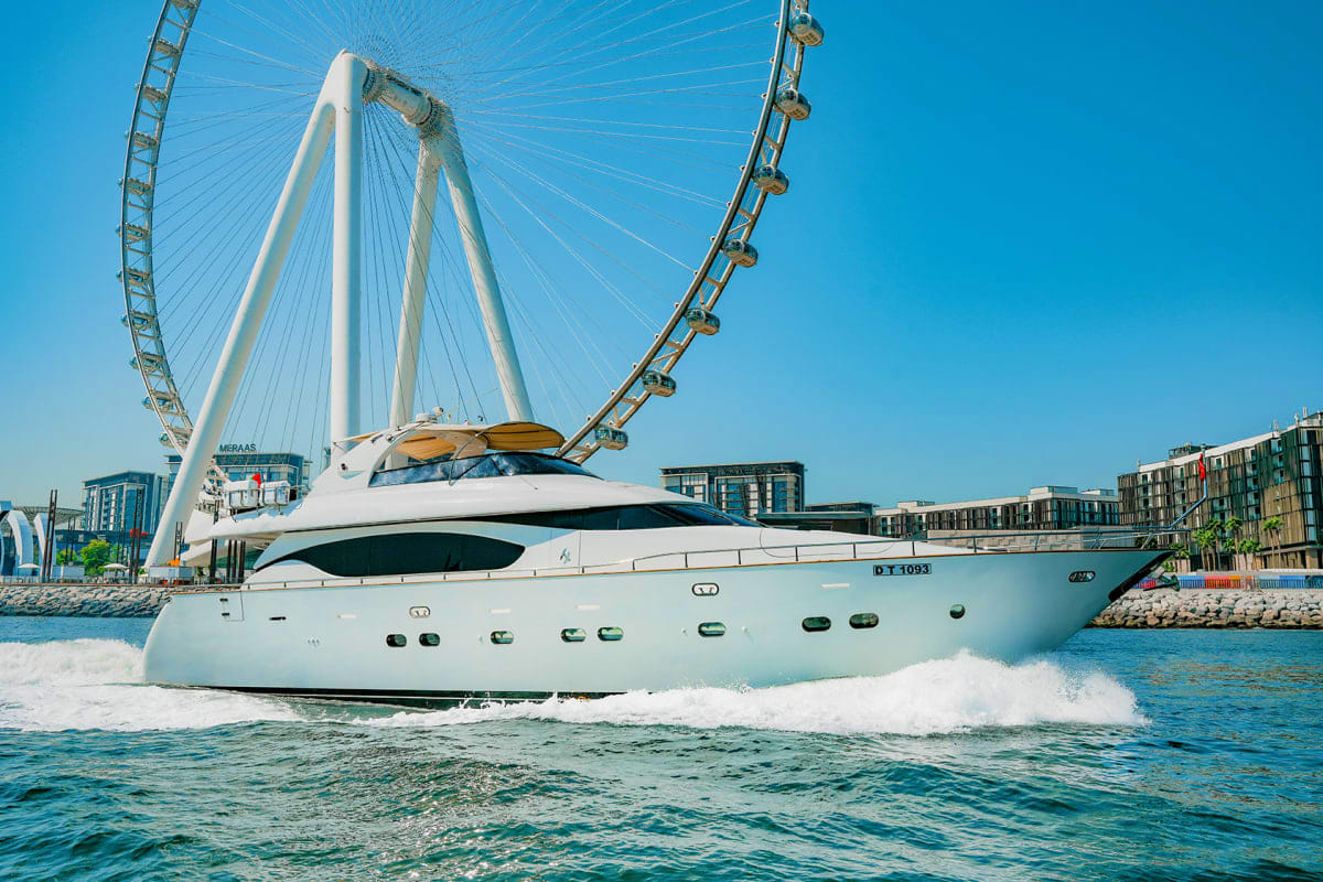 Luxury white motor yacht Maiora X12 anchored in Thames River with London Eye ferris wheel in background under clear blue sky