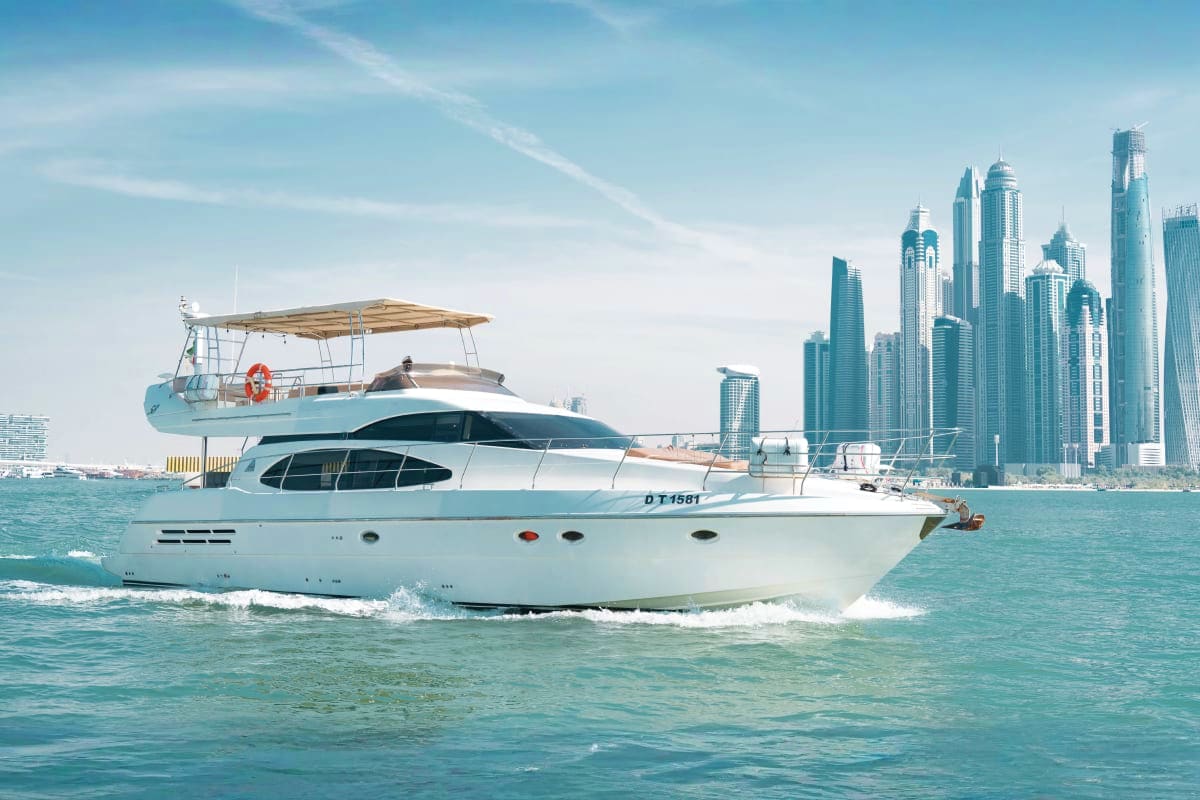Luxury white motor yacht anchored in turquoise waters with Dubai Marina skyline in background