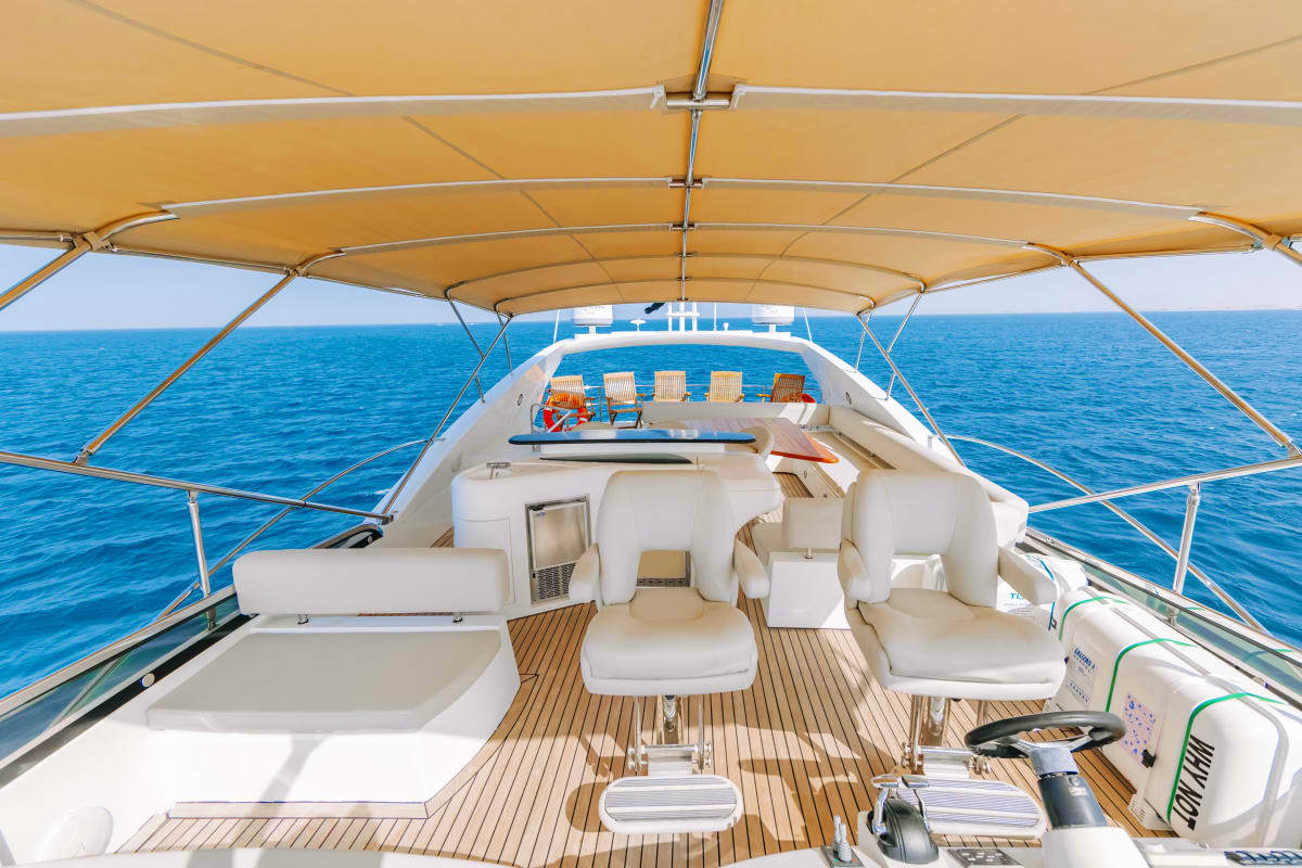 Deck view of 82 Ft Sunseeker Royale Yacht with tan canopy, white seating, wooden flooring, and blue ocean in background