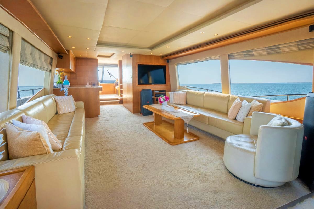 Luxurious interior of 85 Ft KRONOS yacht with cream leather seating, wooden accents, flat-screen TV, and ocean views through