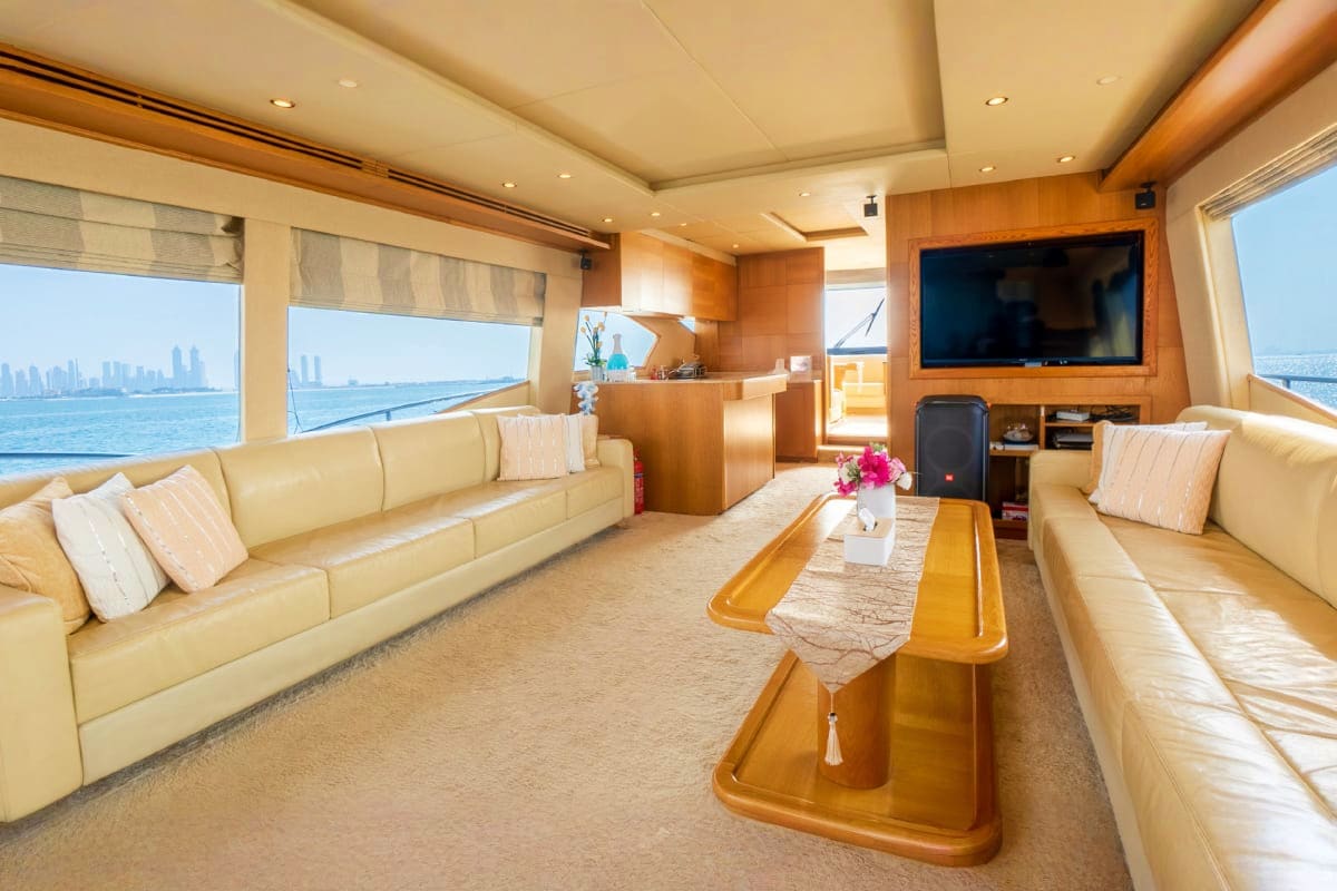 Luxury yacht interior with cream leather seating, wooden accents, flat-screen TV, and ocean views through large windows