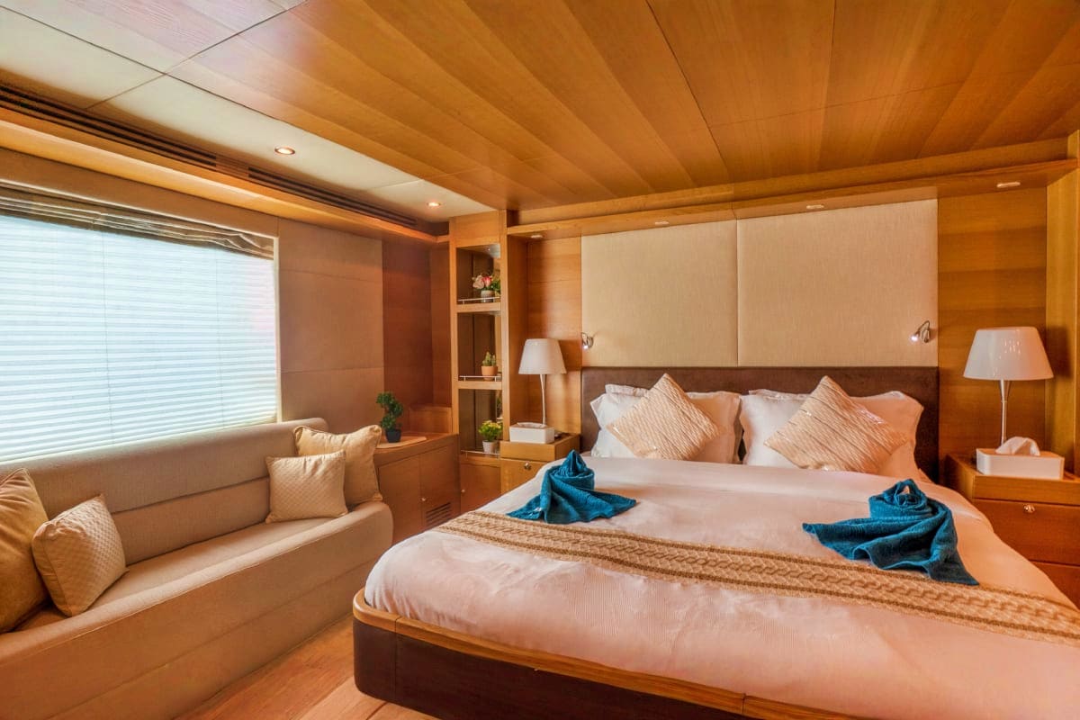 Luxury master bedroom aboard 85 Ft KRONOS Yacht with wooden ceiling, queen bed, seating area, and ocean view window