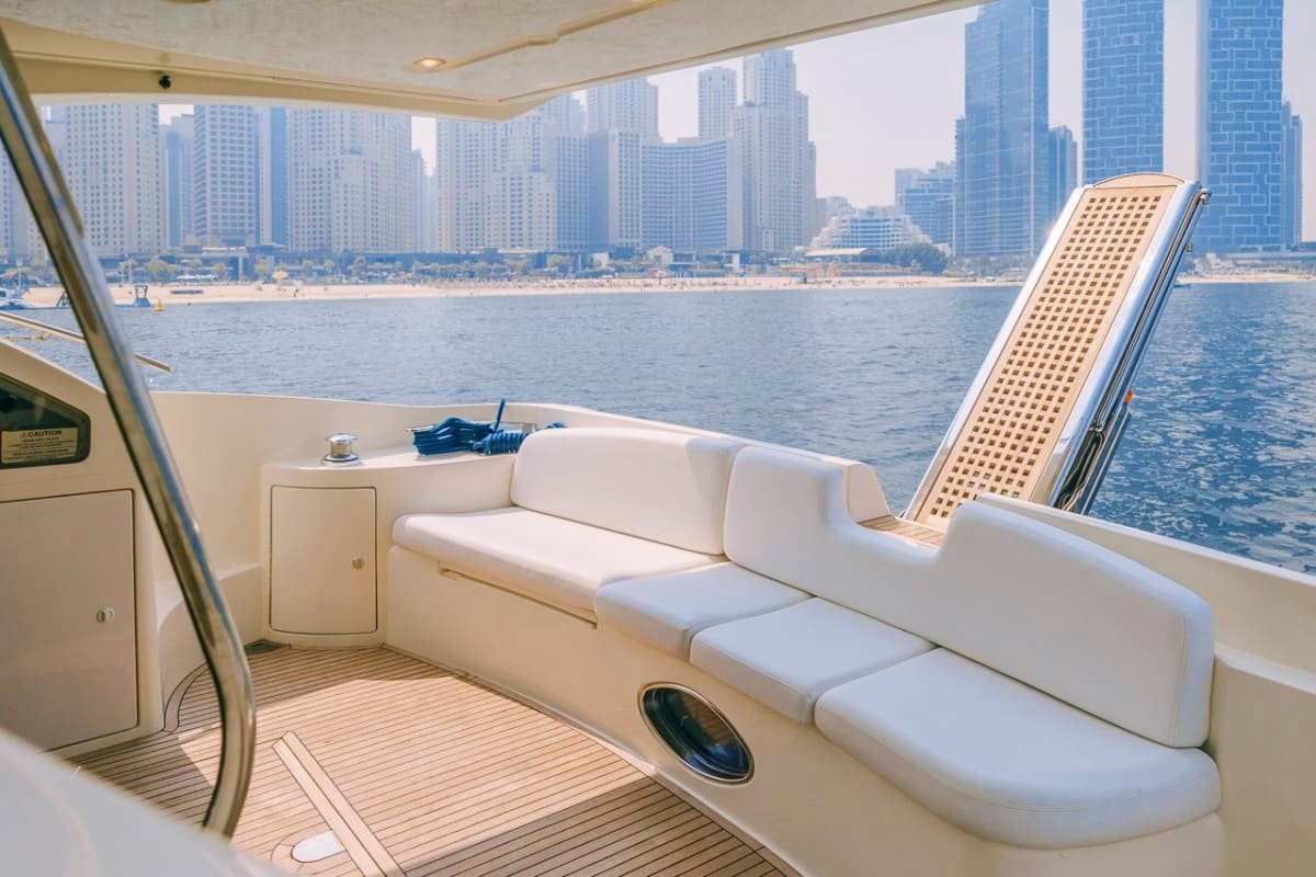 Luxury yacht cabin with white seating, wooden deck, and panoramic windows overlooking San Diego skyline and beach