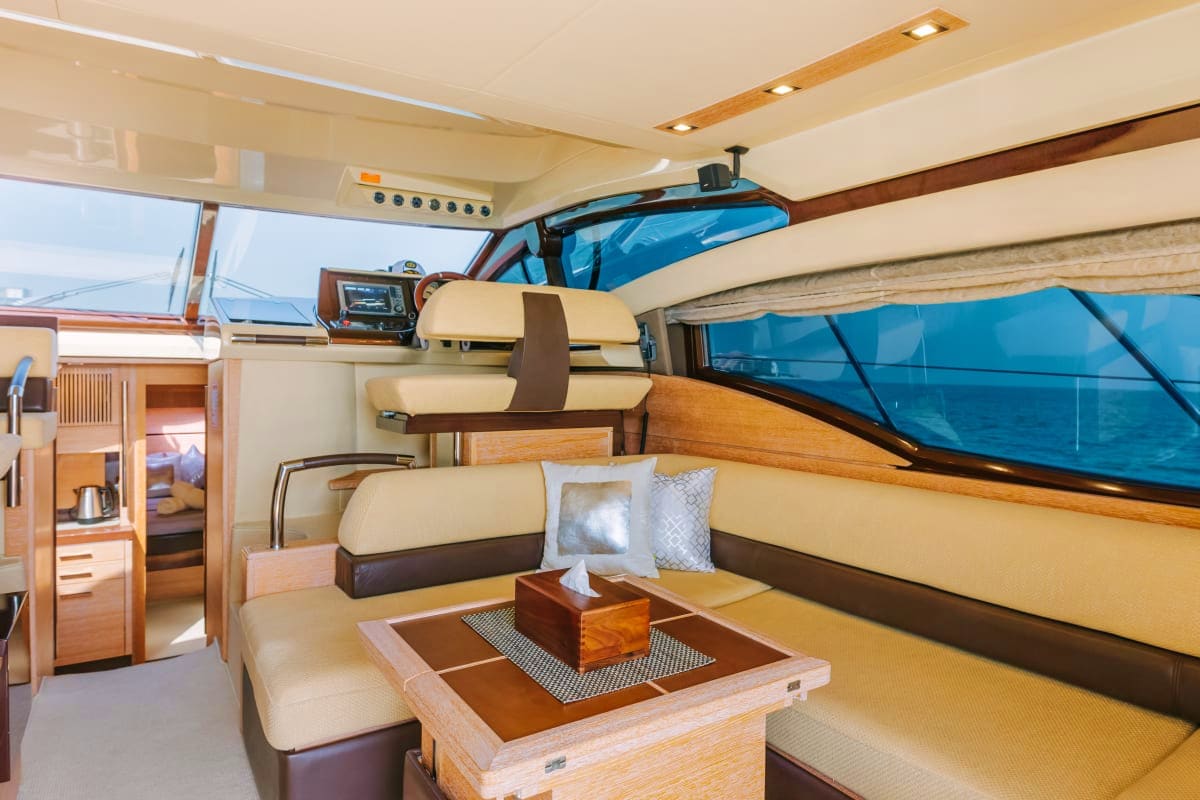 48 Ft Ocean Beat Yacht interior cabin with cream and brown seating, wooden furnishings, and blue ocean views through windows
