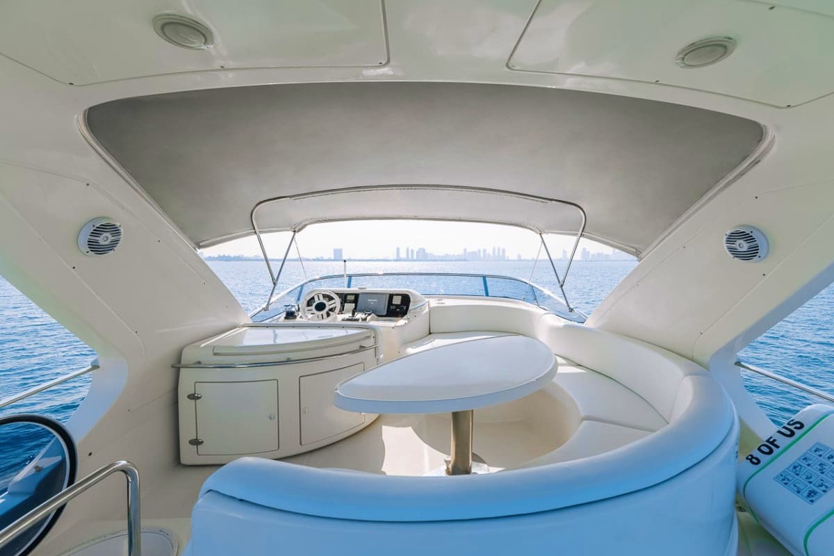 Interior view of 55 Ft Ocean Pulse Yacht cabin with helm station, seating area, and city skyline visible through windshield