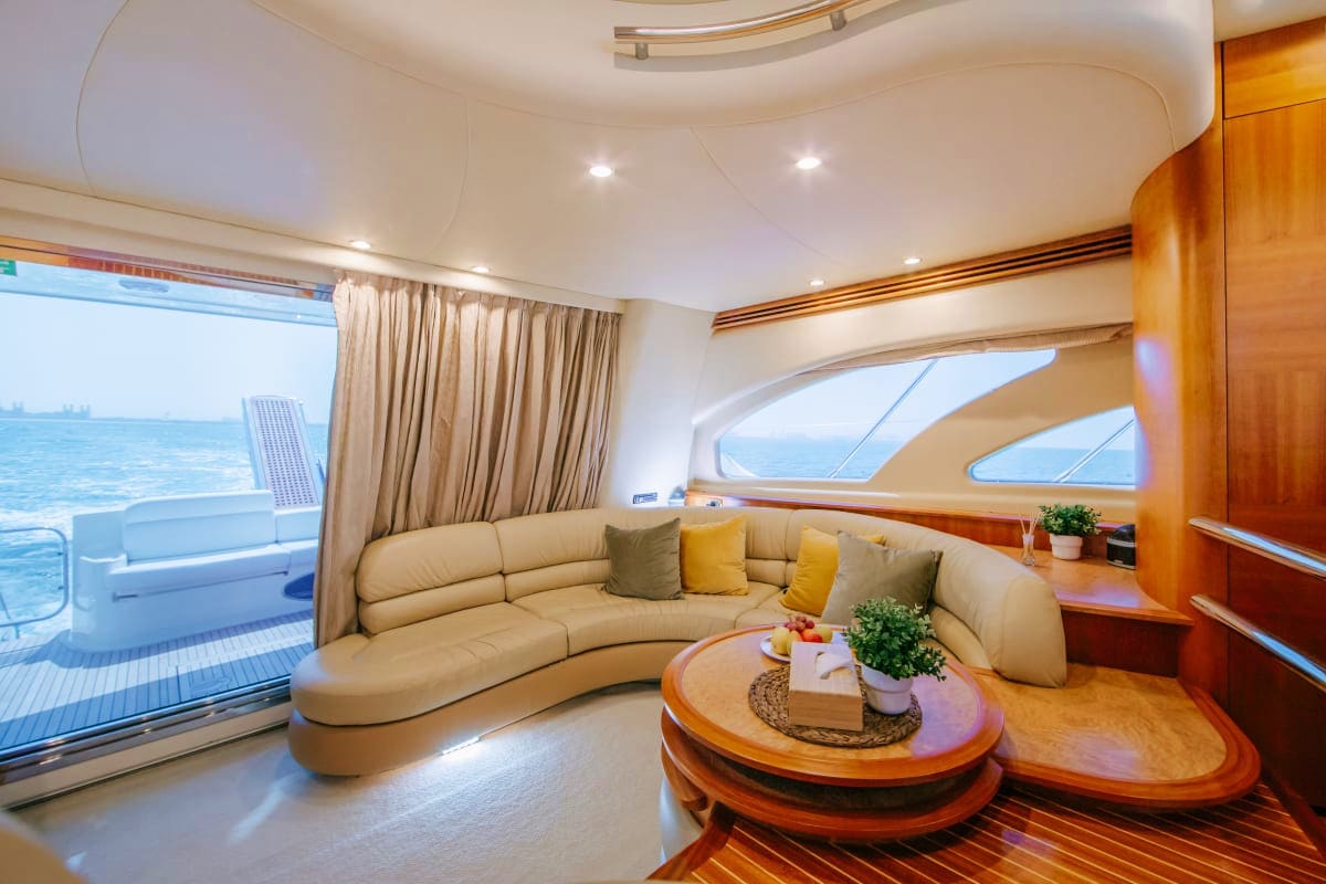 55 Ft Marina Bliss Yacht Modern yacht interior with curved beige sofa, wood accents, ocean view through large windows, and round coffee table