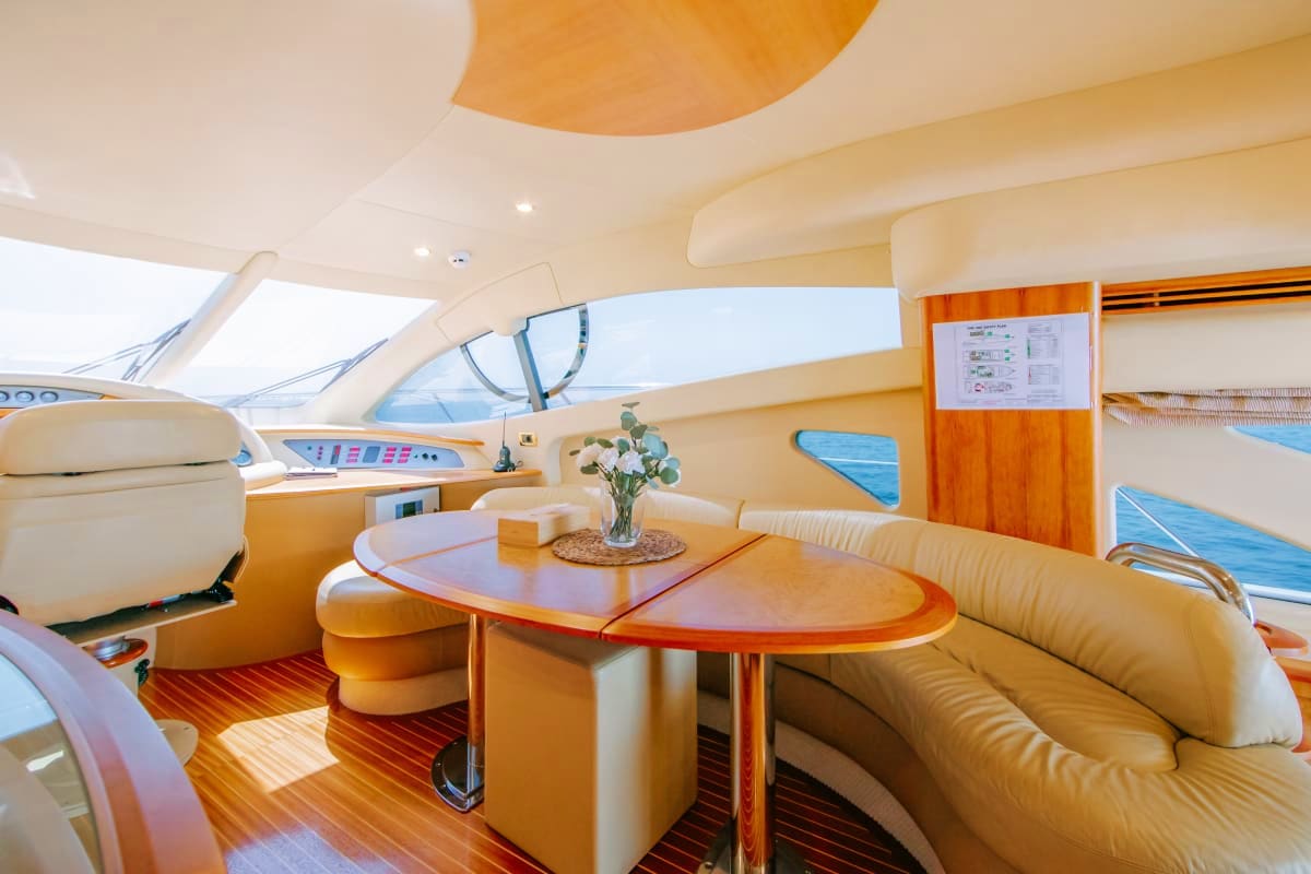 55 Ft Marina Bliss Yacht Luxury yacht interior cabin with cream leather seating, oval dining table, panoramic windows, wood accents, and modern naviga