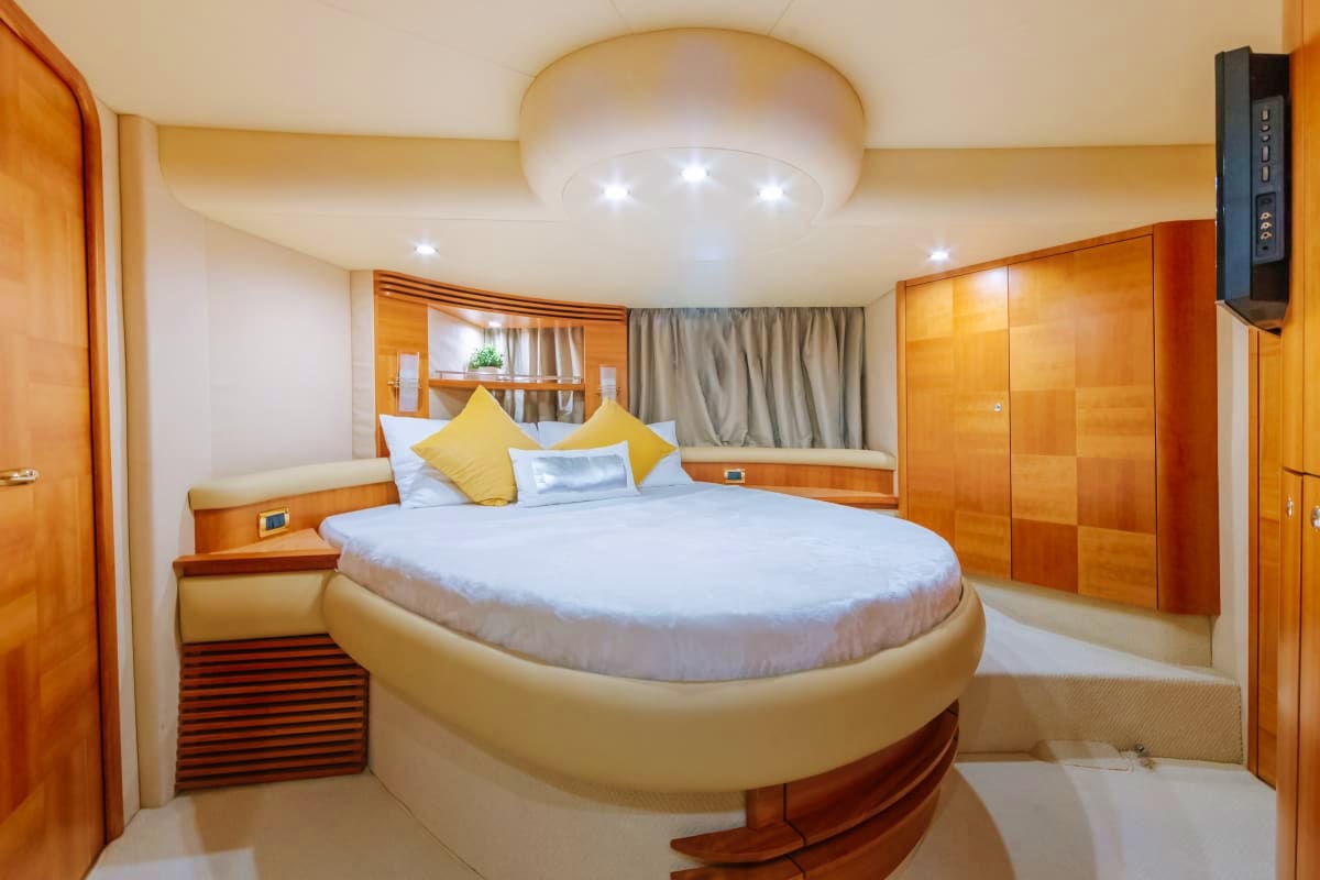 55 Ft Marina Bliss Yacht Luxury yacht master bedroom with round bed, wood cabinetry, yellow pillows, and LED ceiling lighting