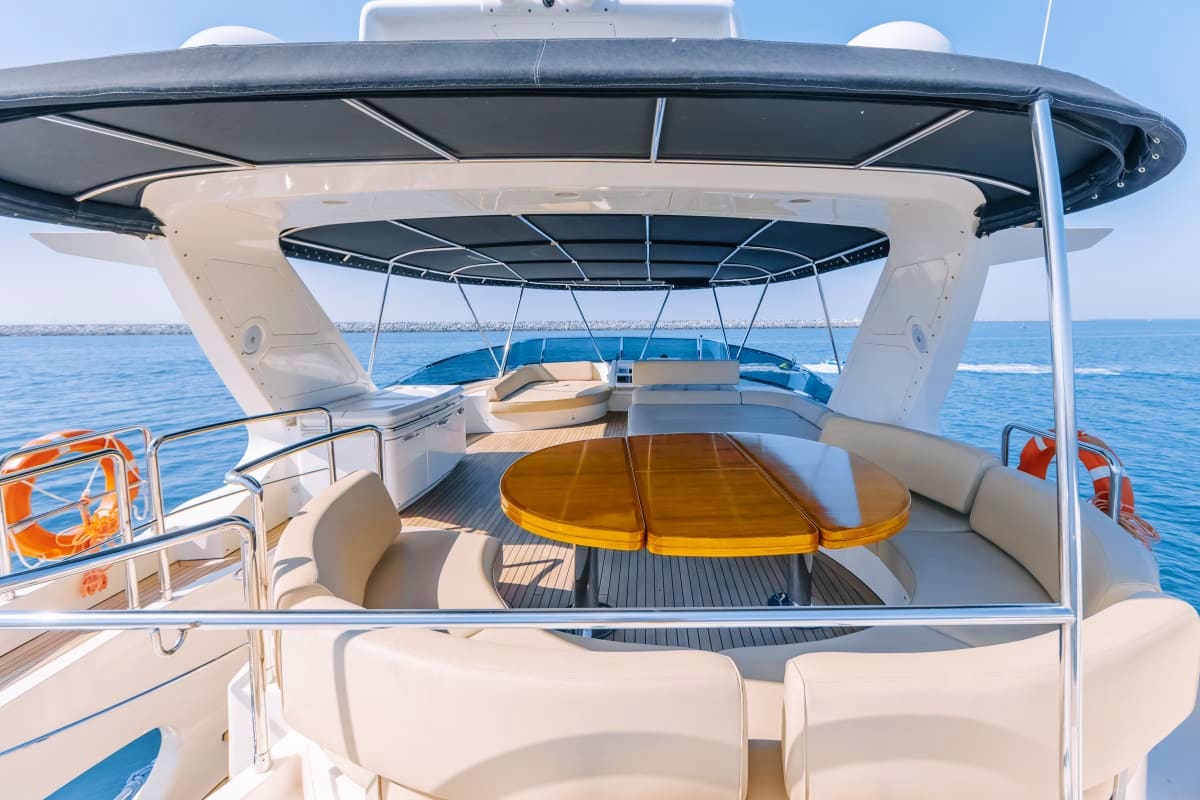 75 Ft Supreme Luxury Yacht 75 Ft Supreme Luxury Yacht deck with golden table, cream seating, black canopy, and blue ocean view