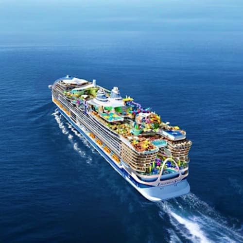 Large modern cruise ship sailing on open ocean with multiple decks and amenities visible from aerial view