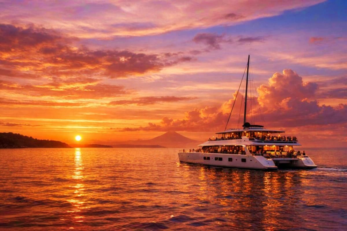 Luxury Bali Indulgence Luxury catamaran sailboat with passengers anchored in calm ocean waters at sunset, with volcano visible on distant horizon