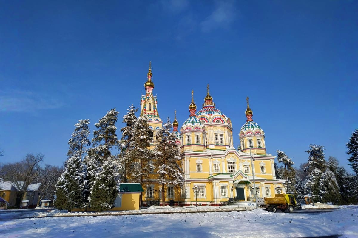 Kazakhstan Super saver Yellow Orthodox cathedral with golden domes surrounded by snow-covered evergreen trees and winter landscape in Kazakhstan