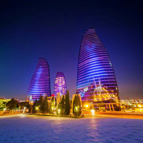 Modern illuminated towers with blue and purple LED lighting at night in Baku, Azerbaijan