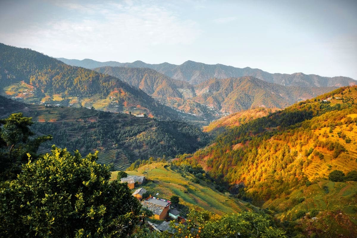 Delhi to Mussoorie Weekend Getaway Scenic mountain valley with terraced farmland, scattered villages, and golden autumn forests in the Himalayas