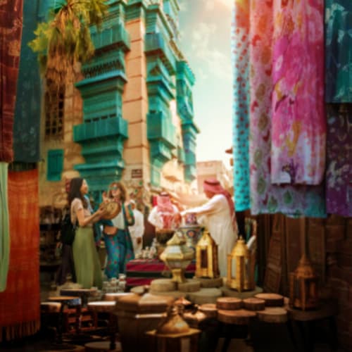 Vibrant street market in historic Saudi Arabian city with colorful fabrics hanging, traditional buildings with turquoise shut