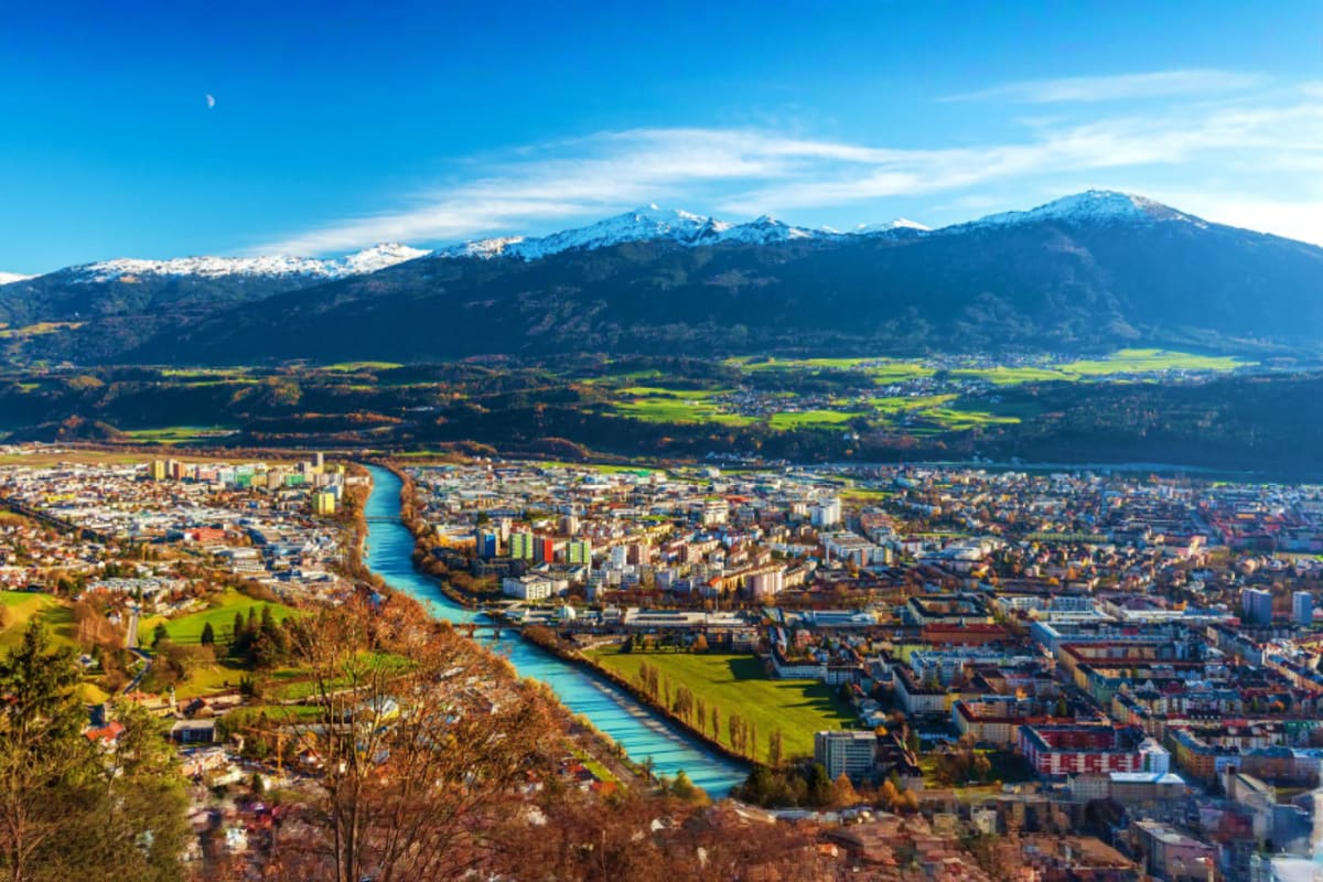 Aerial view of Innsbruck Austria with turquoise river, snow-capped Alps mountains, and valley landscape