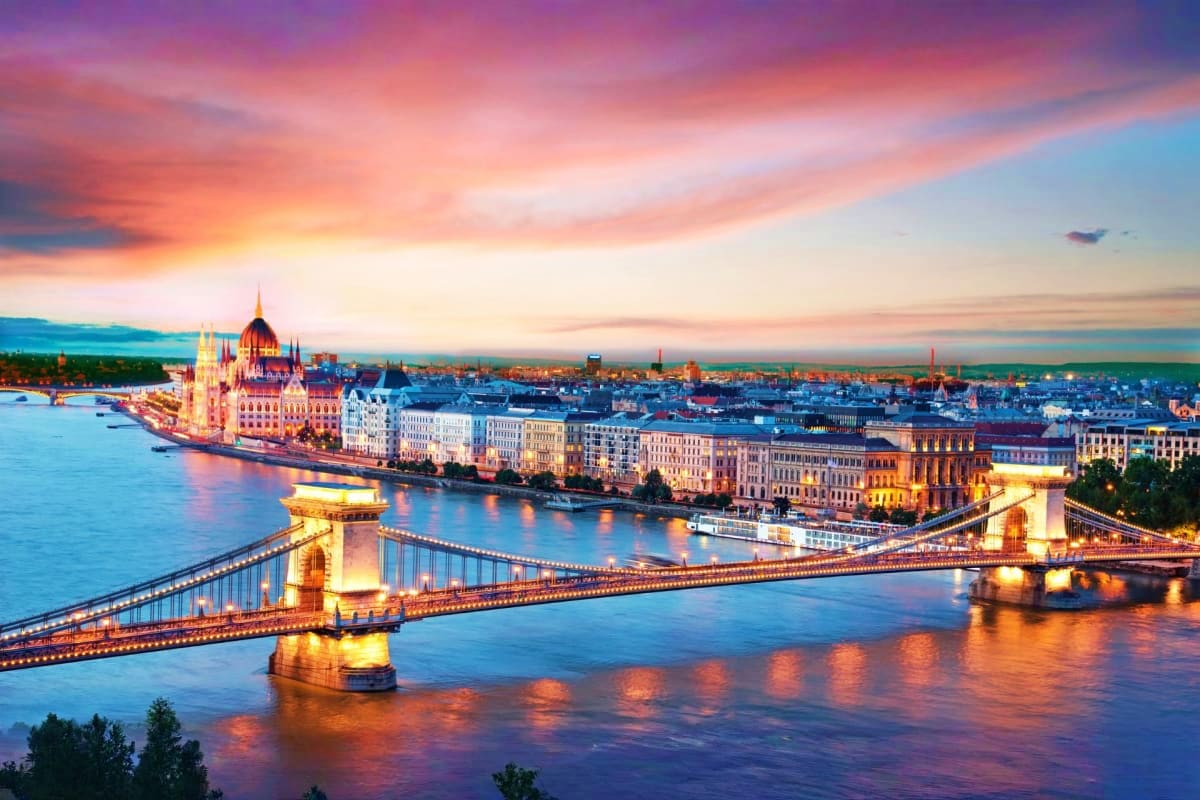 Budapest cityscape at sunset with illuminated Chain Bridge spanning the Danube River and Parliament Building in background