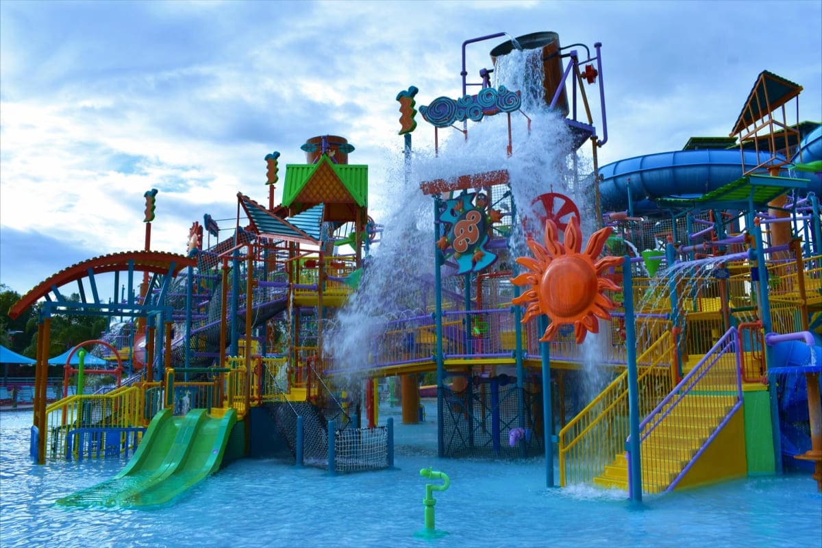 Best of Kuala lumpur and Langkawi Colorful water park play structure with slides, climbing features, and large bucket water feature pouring water on children i