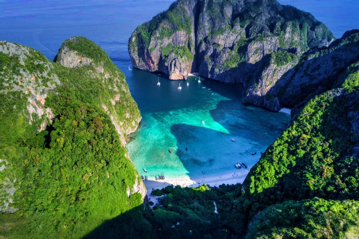 Koh Samui Escape with Phuket and Krabi Aerial view of Phi Phi Leh island's Maya Bay with turquoise waters, white sand beach, limestone cliffs, and anchored boats in