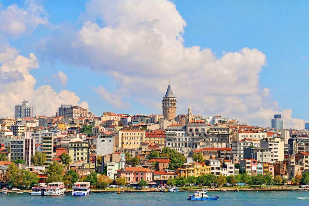 Istanbul waterfront skyline with Galata Tower, colorful buildings, and ferry boats on the Golden Horn